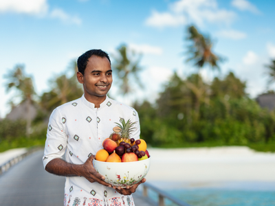 A personal butler at The Nautilus Maldives holding a bowl of fruits