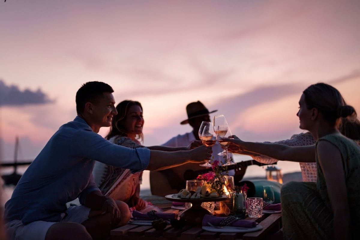 A group of friends toasting with champagne on the beach at The Nautilus Maldives